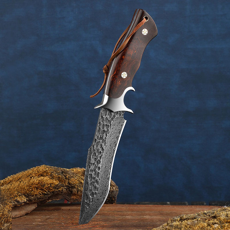 Odin's Edge Damascus knife with VG10 steel core and natural rosewood handle stuck vertically in wood