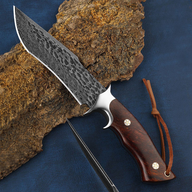 Odin's Edge Damascus steel fixed blade knife resting on stone showing craftsmanship details