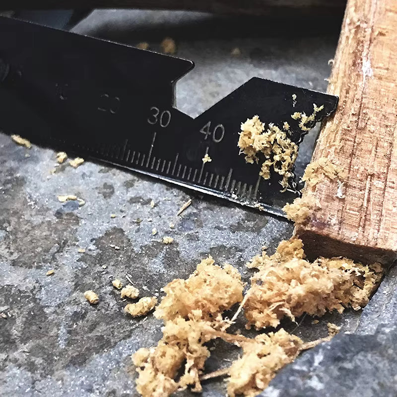Macro shot of Sparkforge Rod striker carving wood to make fine tinder shavings for ignition. Shows serrated scraper edge, curved tip, and high-quality metal craftsmanship for reliable spark generation.
