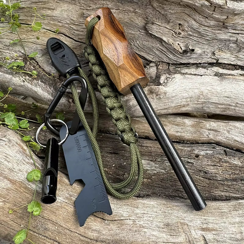 Full Sparkforge Rod Tactical Fire Starter kit displayed on natural wood surface — includes magnesium fire rod with hammer-patterned handle, multi-tool striker with ruler, whistle, carabiner, and adjustable paracord lanyard. Reliable survival ignition tool for outdoor use.